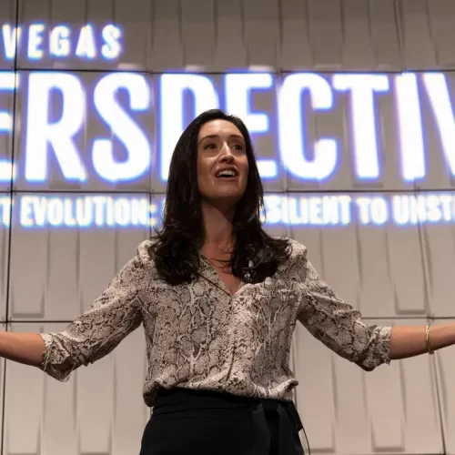 Erica Orange with arms outstretched to the audience, with "Las Vegas Perspective Our Next Evolution: Resilient to Unstoppable" projected behind her